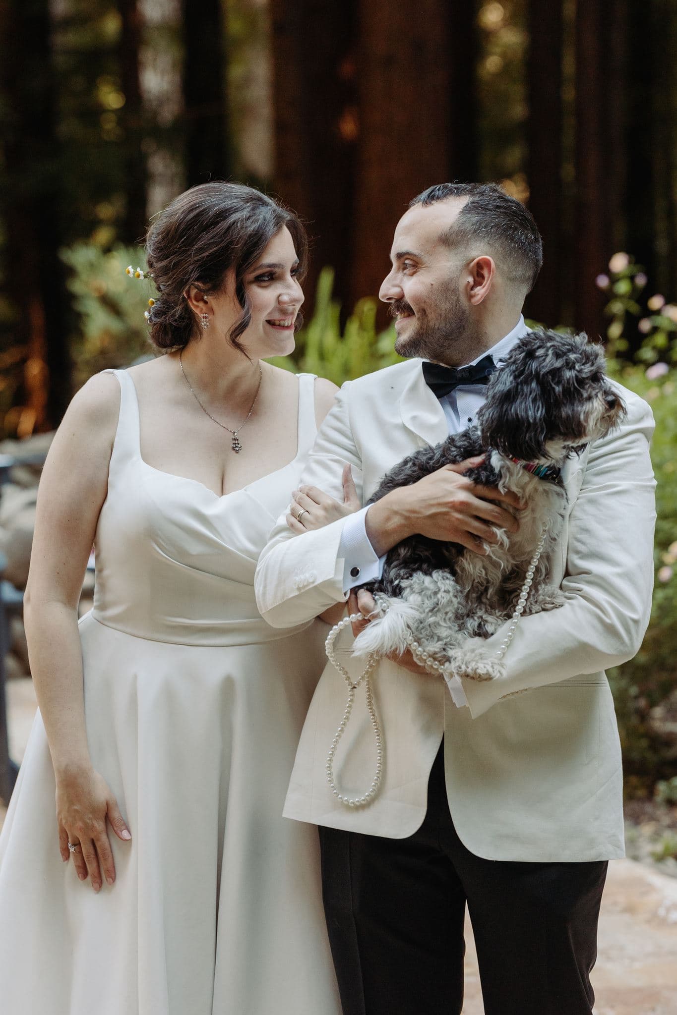 Ilayda and her husband holding their dog in a redwood forest at their wedding
